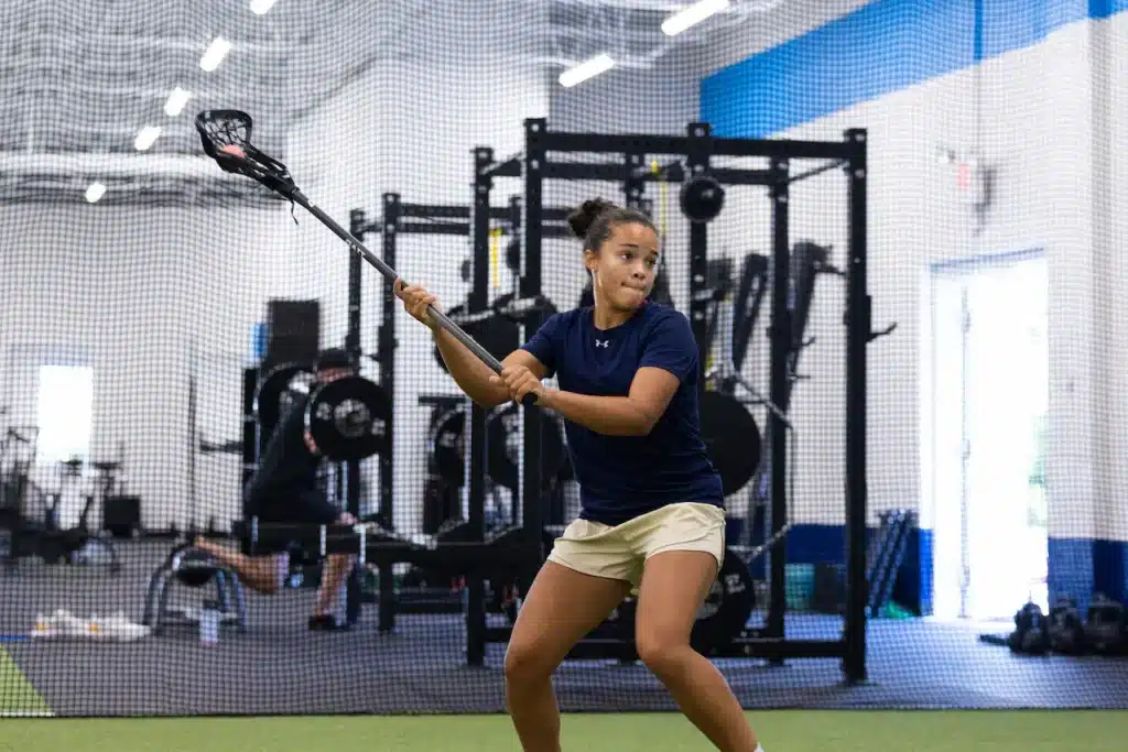Woman practicing lacrosse indoors at the gym.