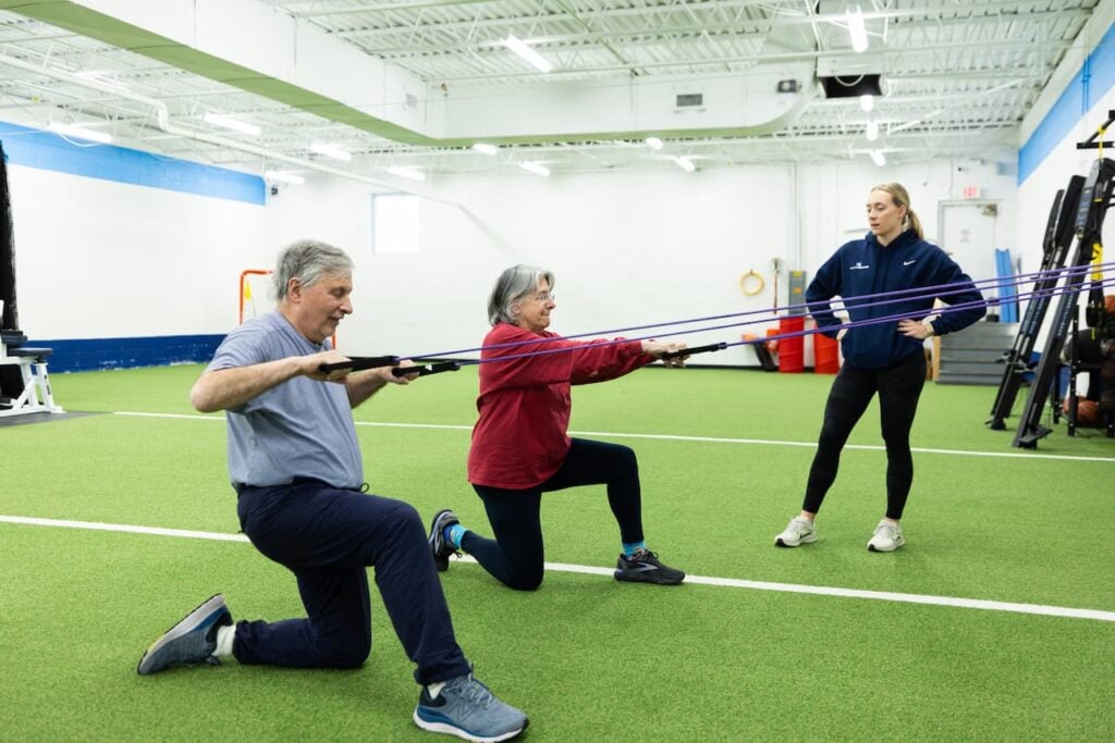 Senior couple exercising with trainer in gym