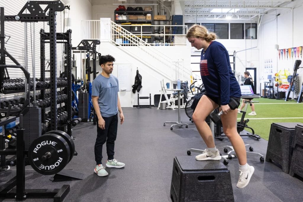 Gym training with step-ups and dumbbells.
