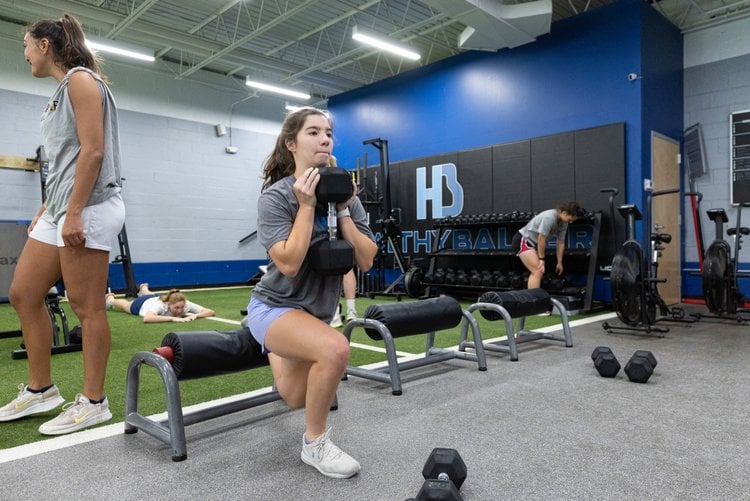 Women exercising with gym equipment in fitness center.