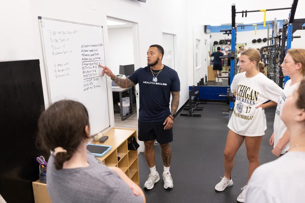 Trainer explaining workout plan to group in gym.