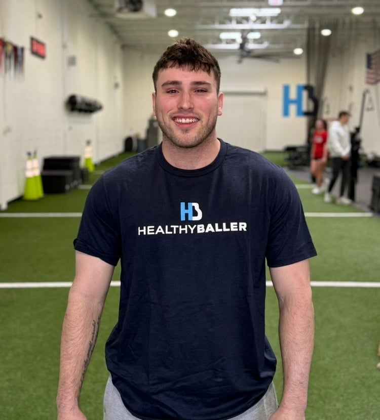 Smiling person wearing Healthy Baller shirt in gym.