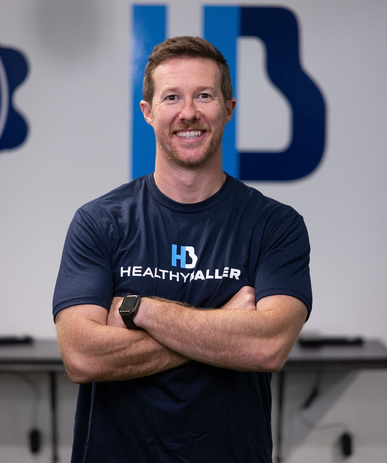 Man in Healthy Baller shirt smiling indoors.