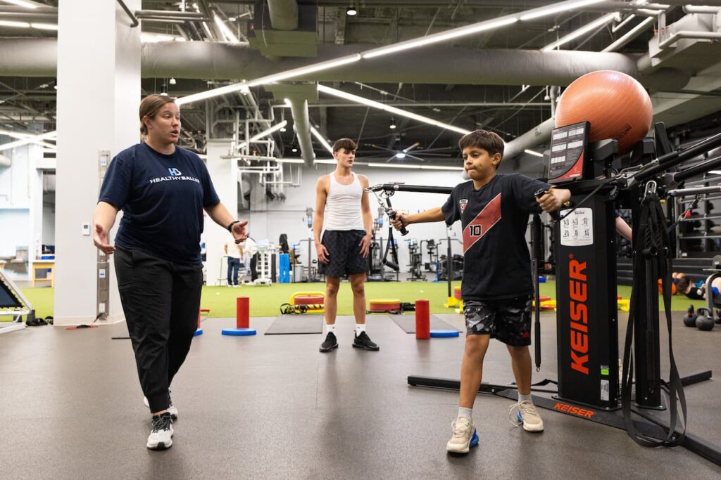 Trainer guides kids in gym workout session.