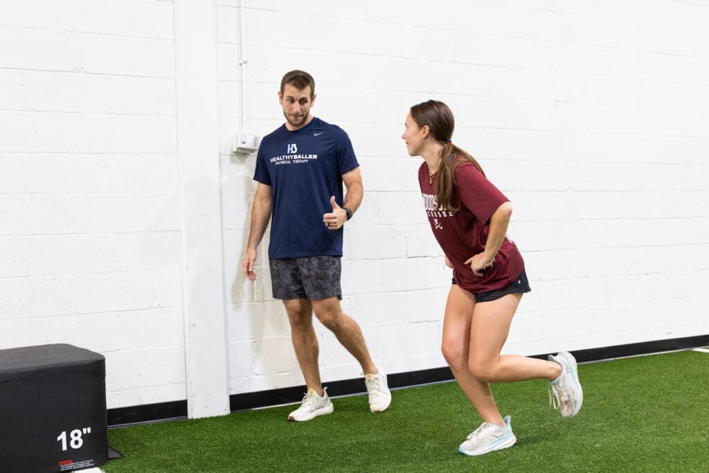 Trainer guiding woman during exercise in gym.
