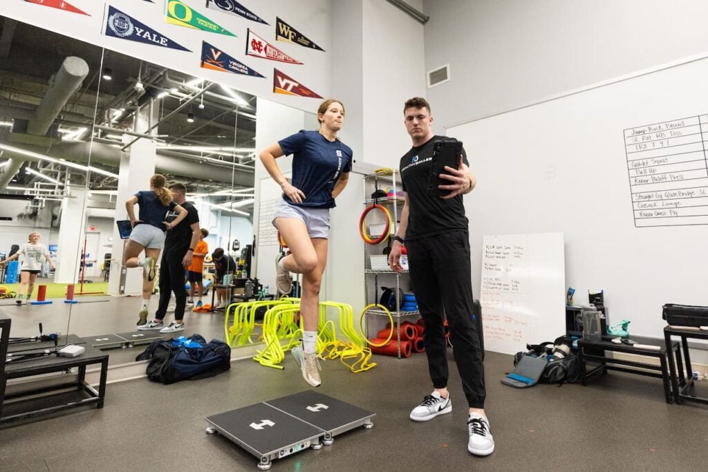 Trainer and athlete at gym practicing balance exercises.