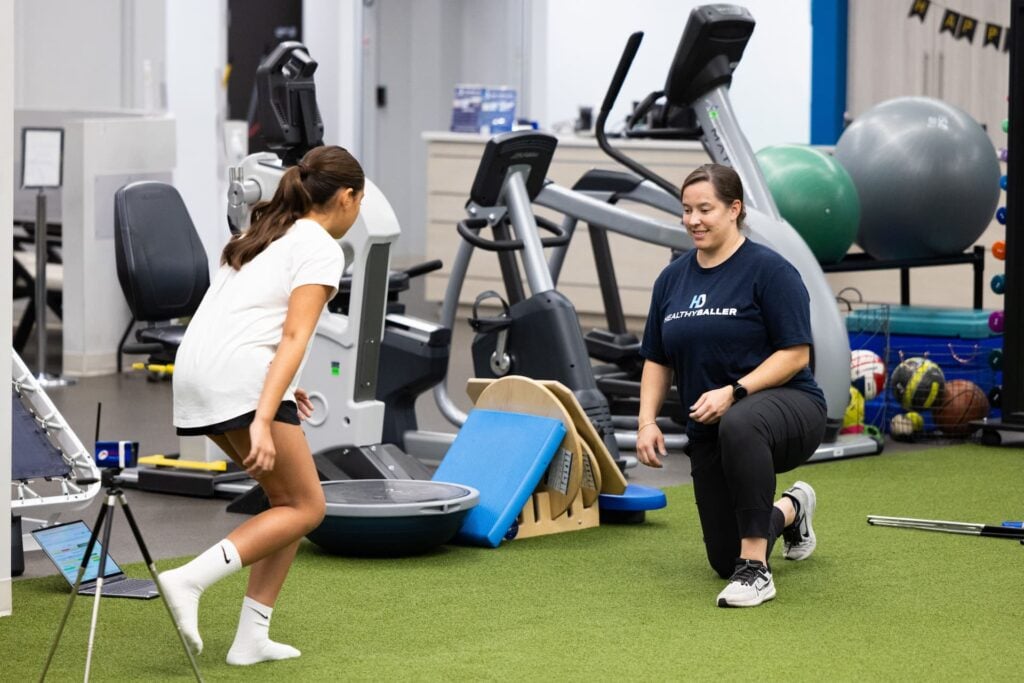 Child and trainer exercising in gym setting.