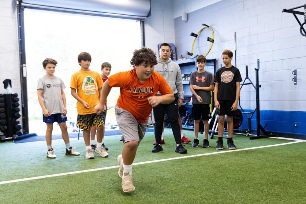 Boys practicing sprints indoors at sports facility.
