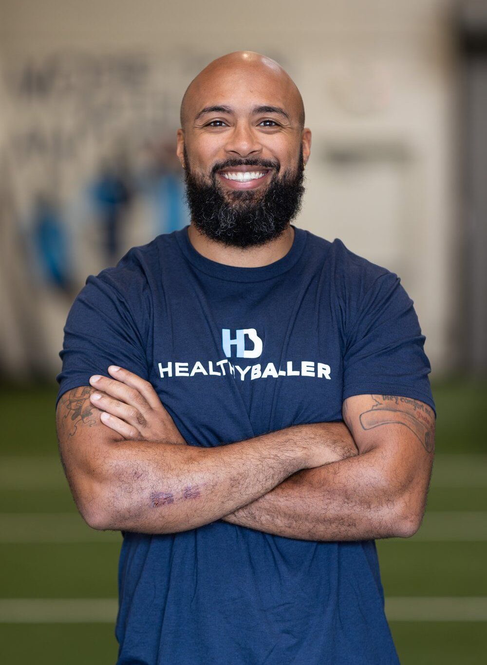 Smiling man in HealthyBaller shirt arms crossed