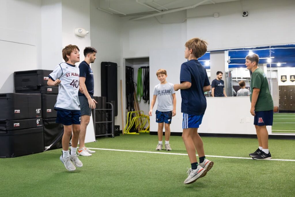 Kids exercising with coach in indoor gym