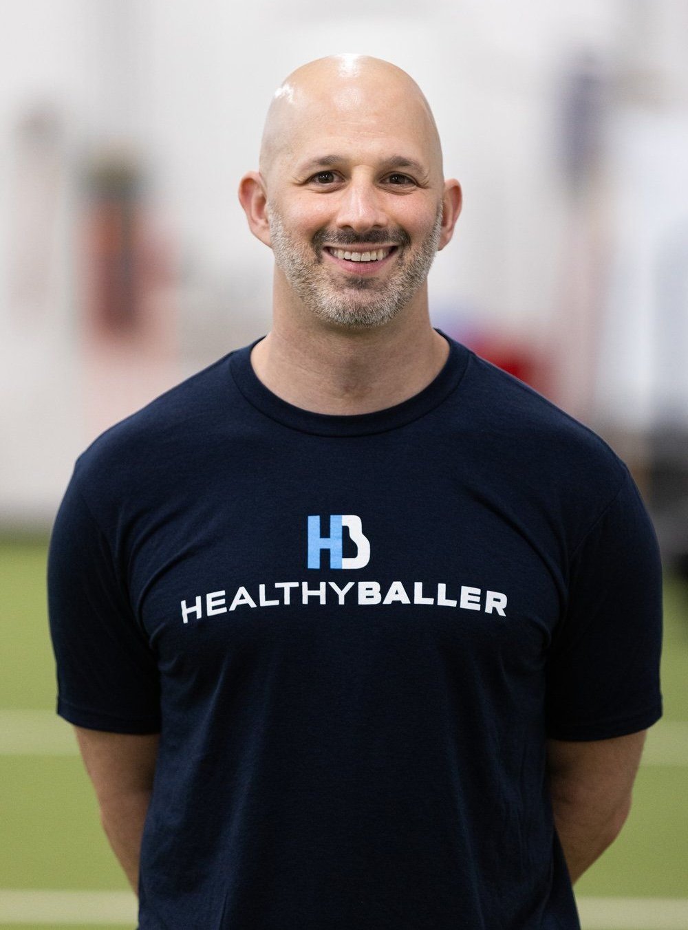 Smiling man wearing Healthy Baller t-shirt indoors.