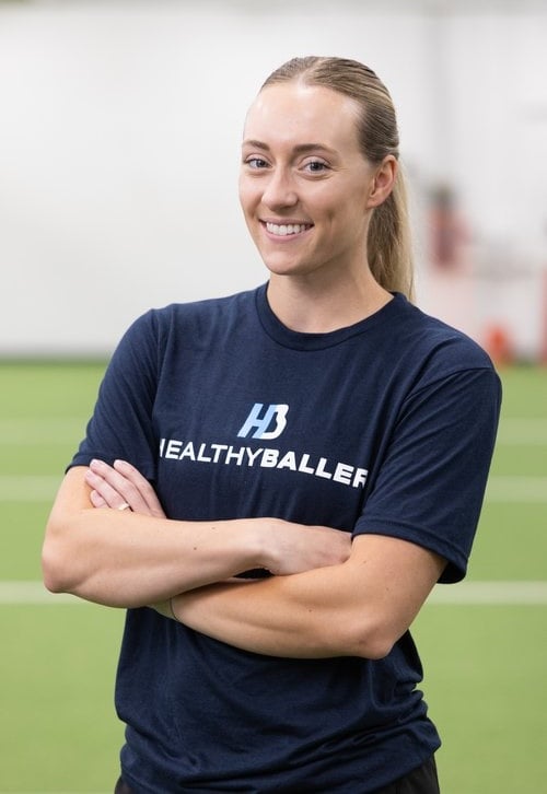 Person smiling wearing "Healthy Baller" shirt indoors.