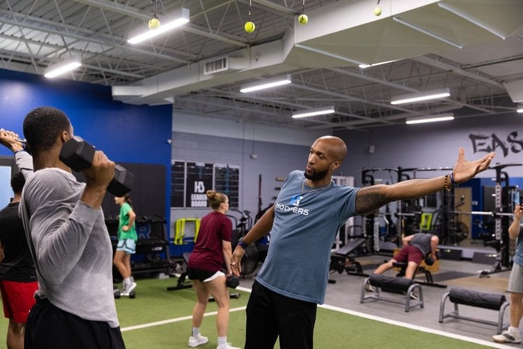 Trainer instructing workout in gym with weights