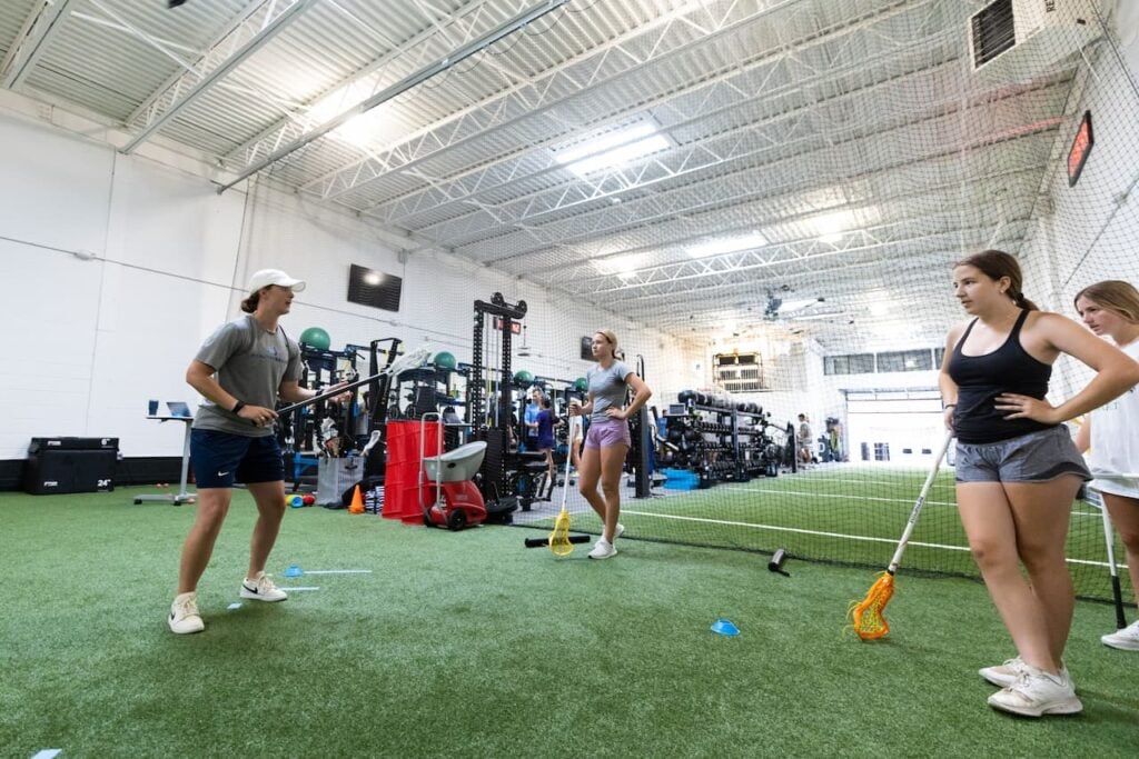 Indoor lacrosse practice with athletes and equipment.