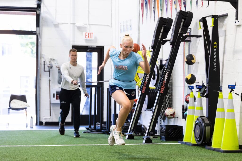 Athlete sprinting indoors with a coach