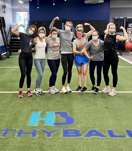 Group of masked women flexing in gym.