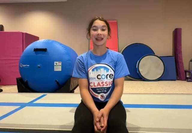 Young gymnast sitting in gymnastics training room.