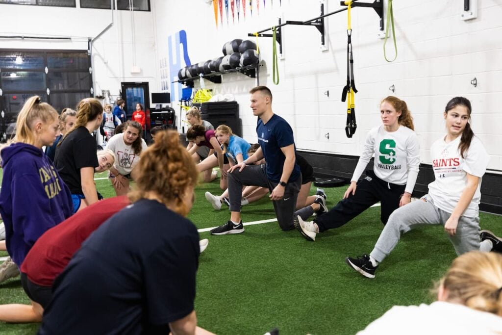 Coach leads volleyball team in stretching exercises.