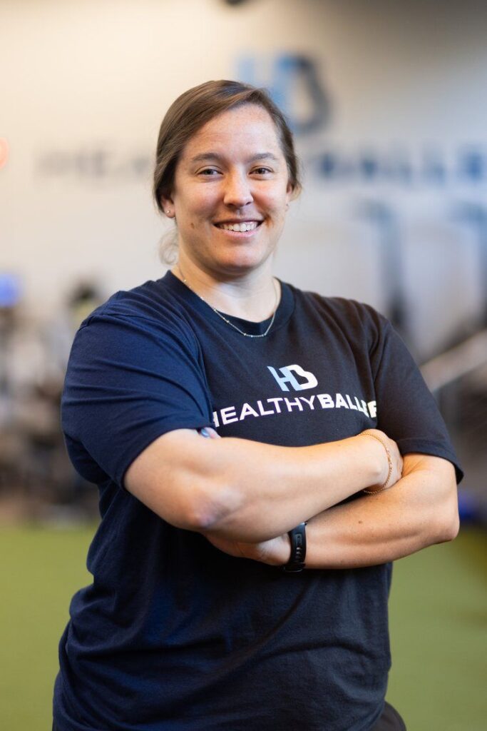 Smiling person in sports center, arms crossed.