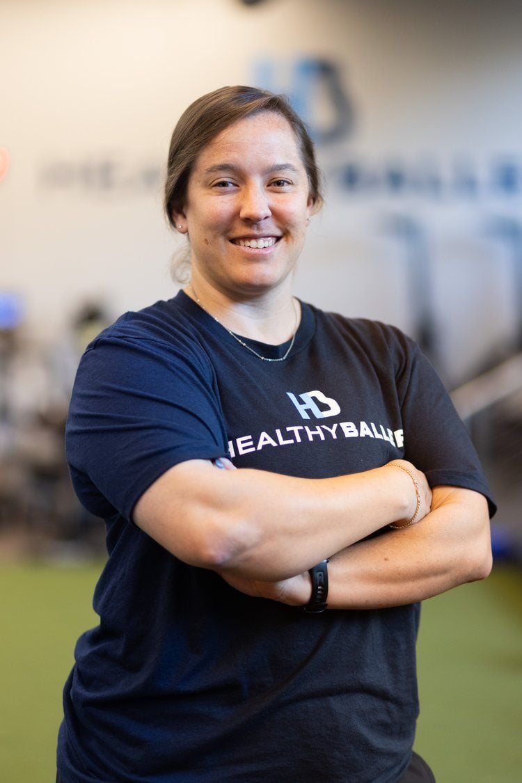 Smiling person in sports center, arms crossed.