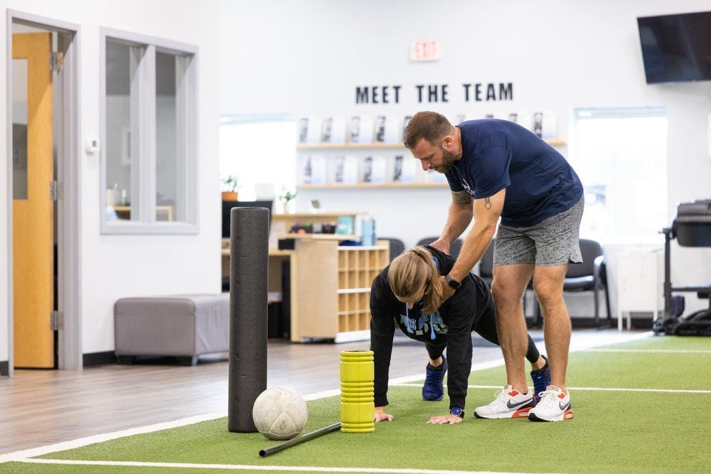 Trainer assists client with exercise in gym.