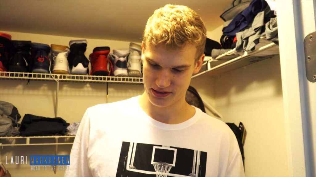 Person in closet with sneakers and shirts visible.