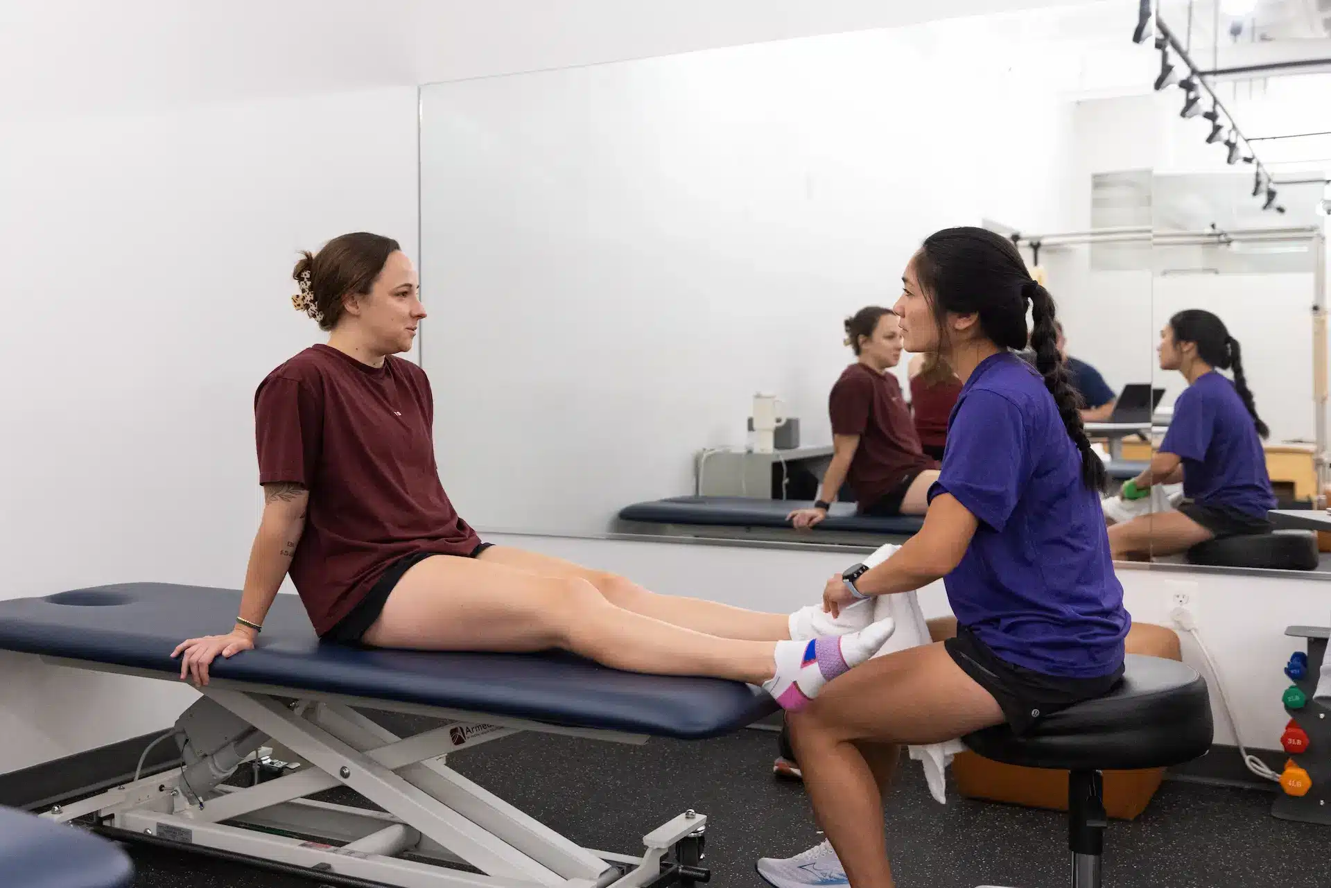 Physical therapist examining patient's legs on table.