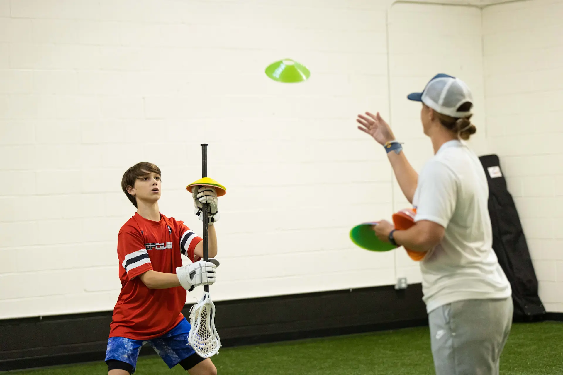 Lacrosse training indoors with cones and stick practice.
