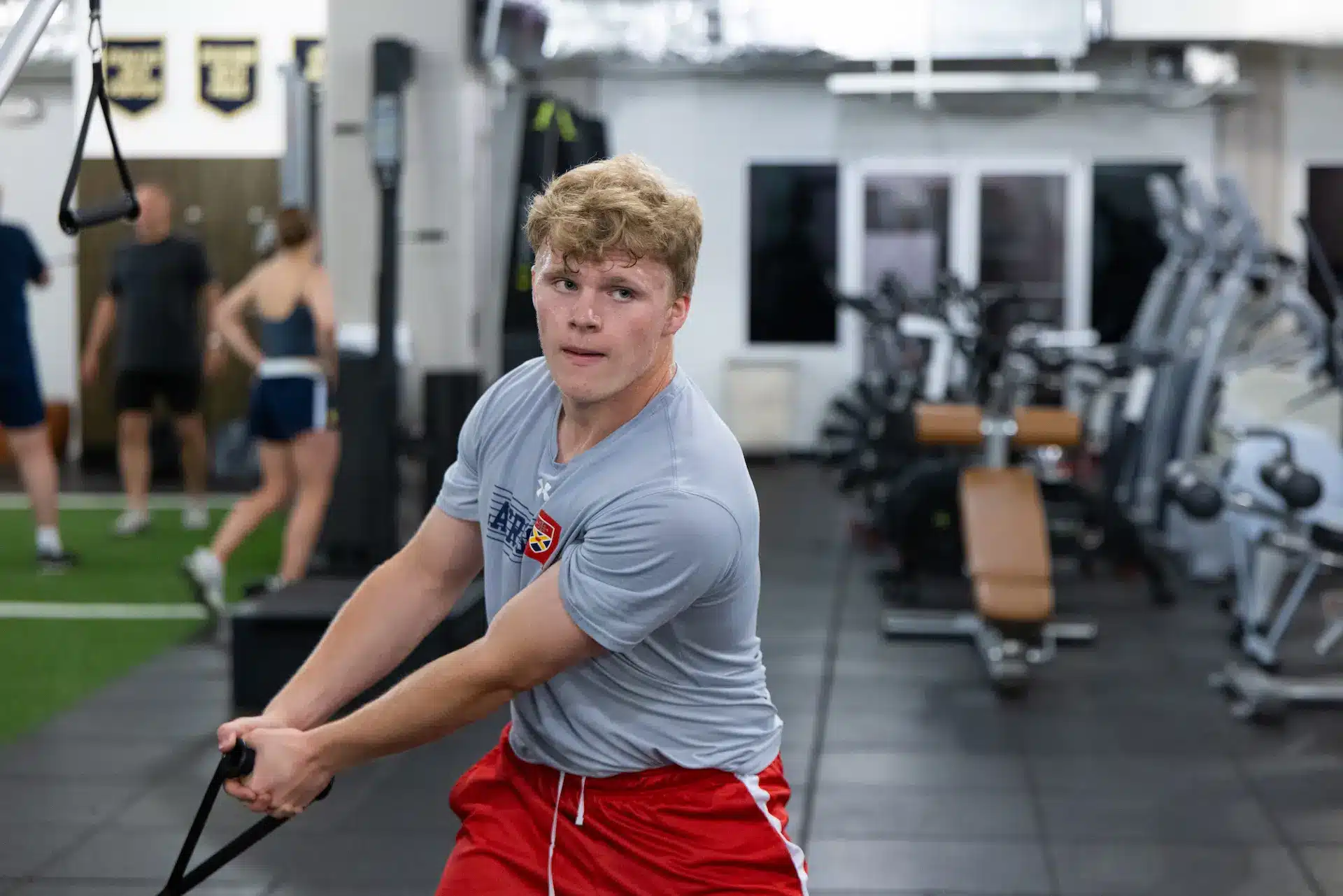 Person exercising in gym with cable machine.