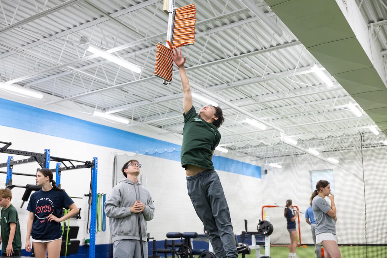 Person reaching for height measurement in gym.