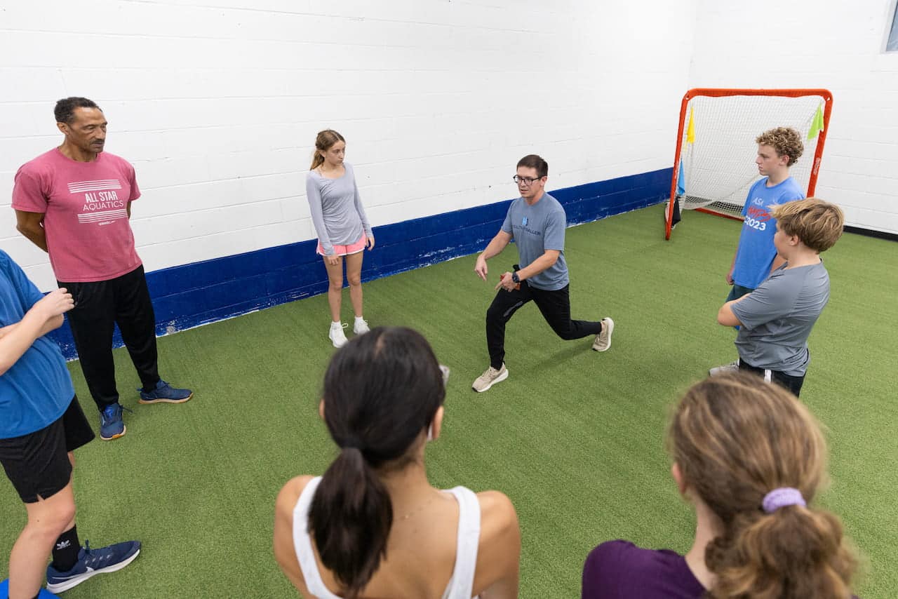 Coach demonstrating exercise to group of youth athletes.