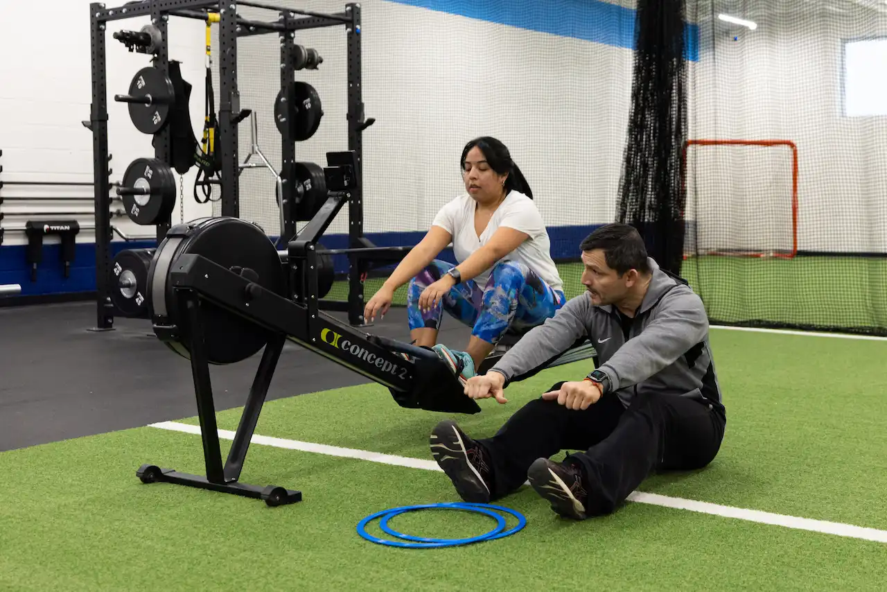 Two people practicing rowing at the gym.