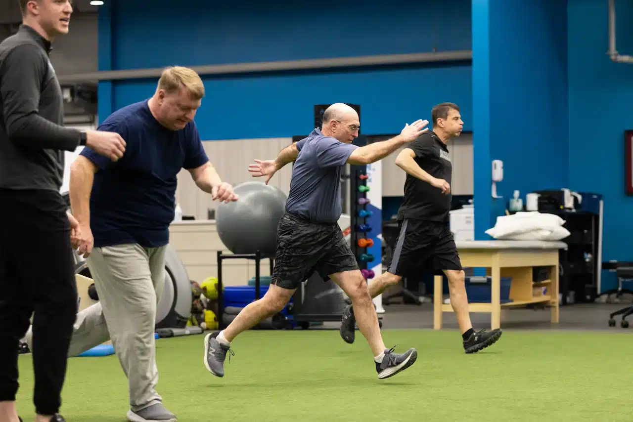 Men exercising indoors on green turf.