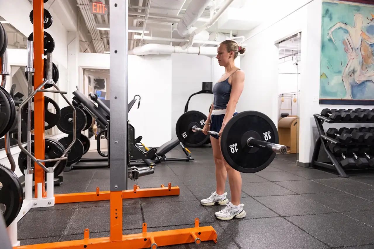 Person performing deadlift in gym setting.