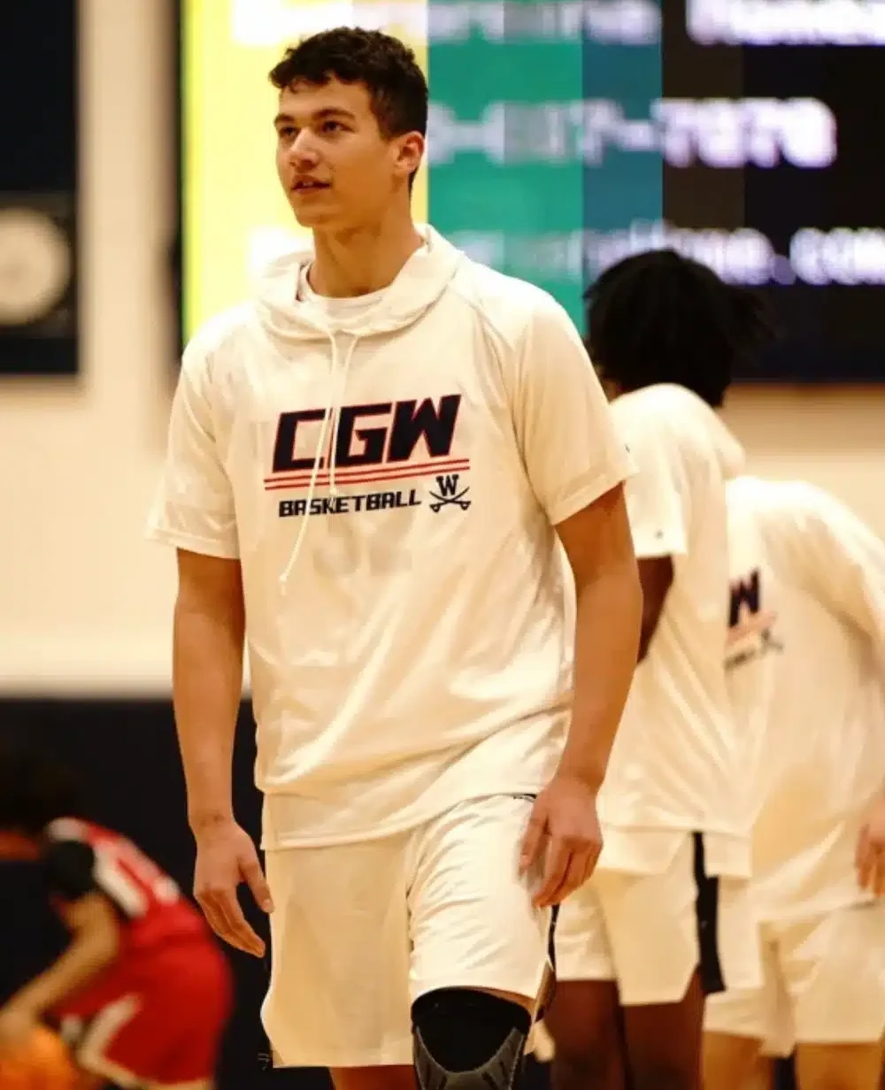 Basketball player in white CGW shirt on court.