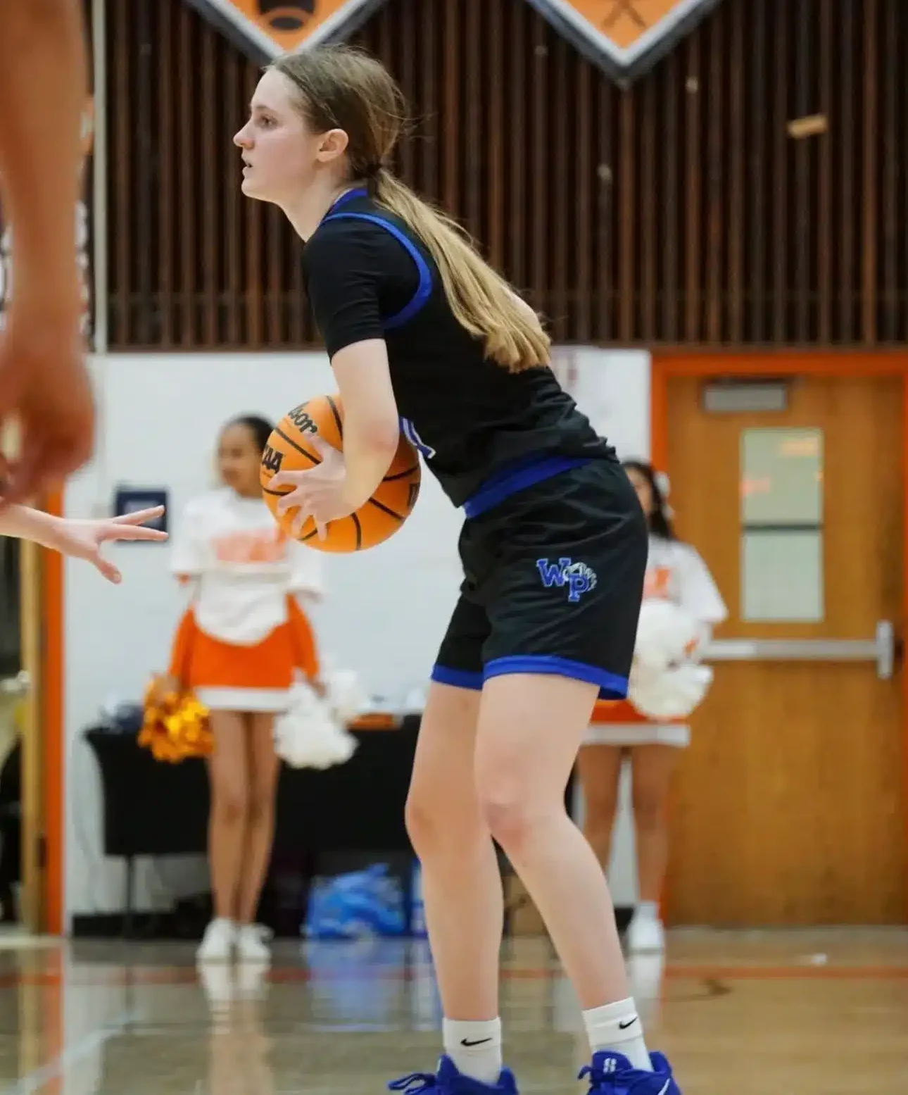 Girl playing basketball in a gymnasium.