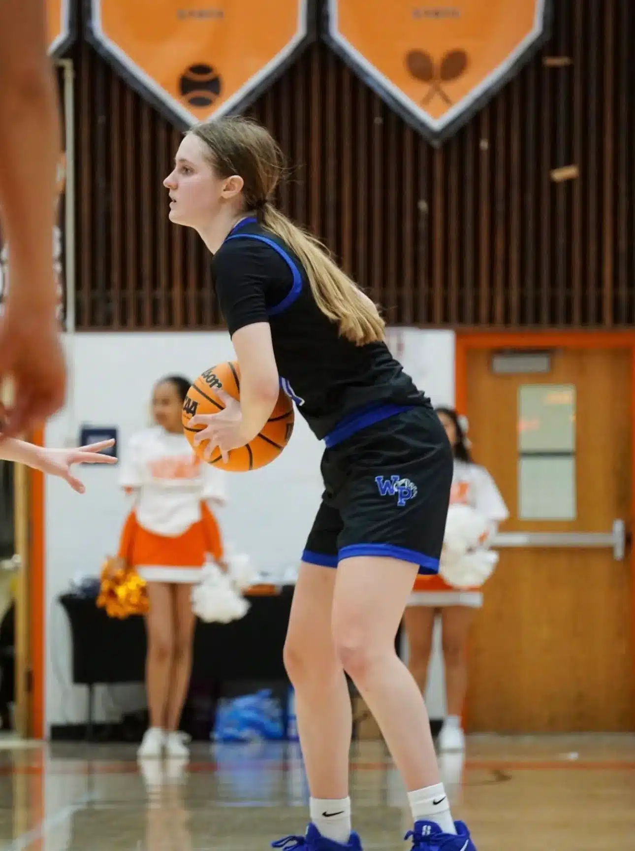 Girl playing basketball in a gymnasium.