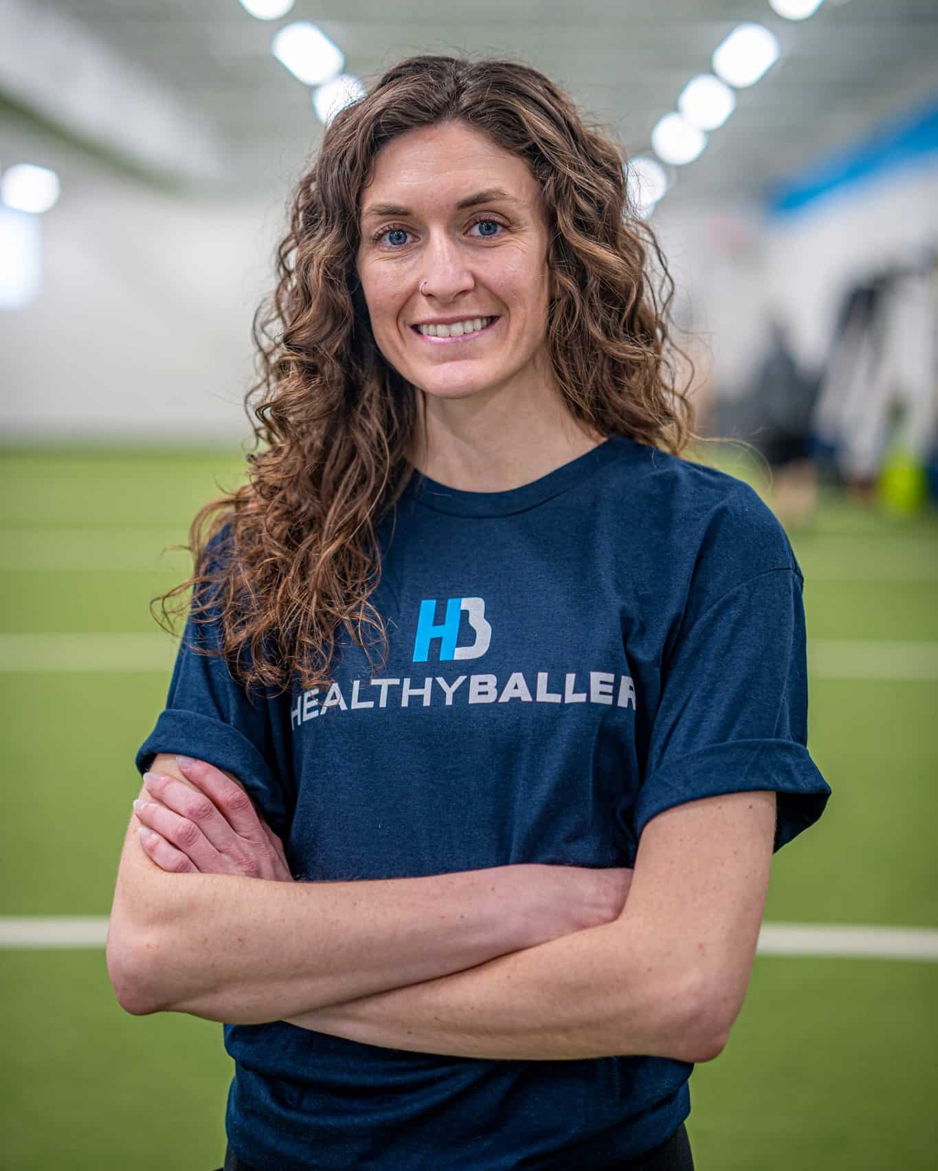 Woman in gym with Healthy Baller shirt smiling.