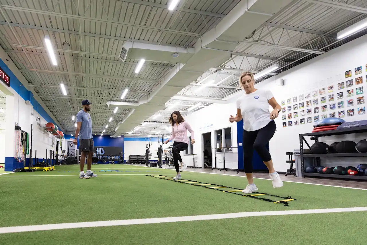 People exercising in a gym with agility ladder