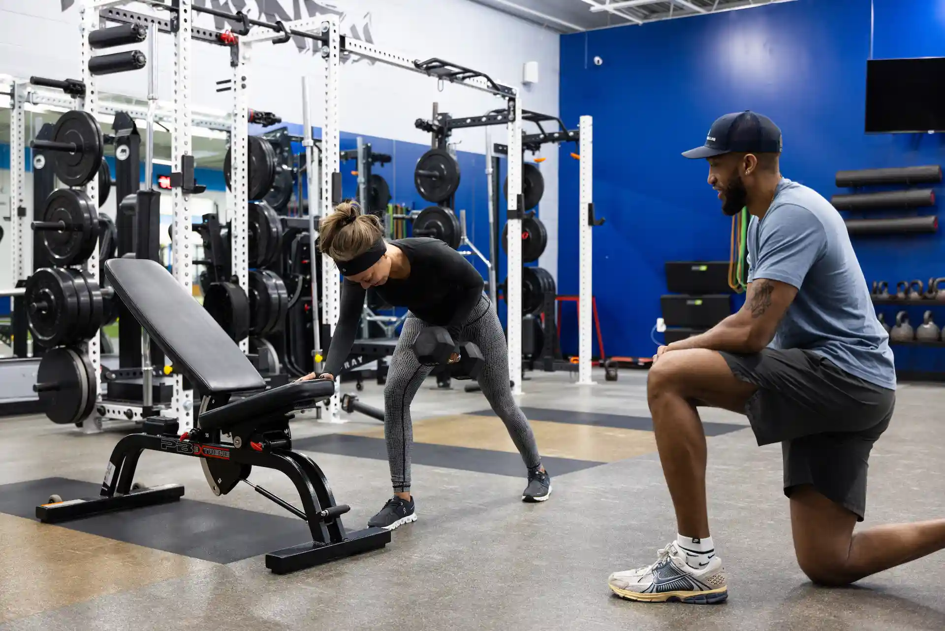 Woman lifting weights with trainer in gym