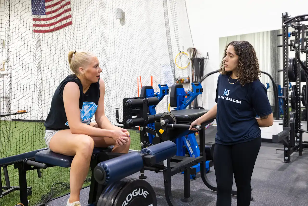 Two women talk beside gym equipment indoors