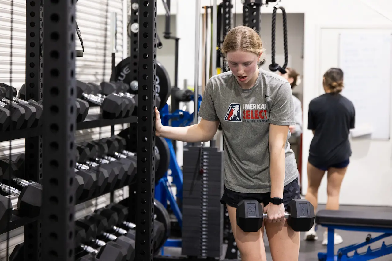 Athlete performs dumbbell exercise in a weight room