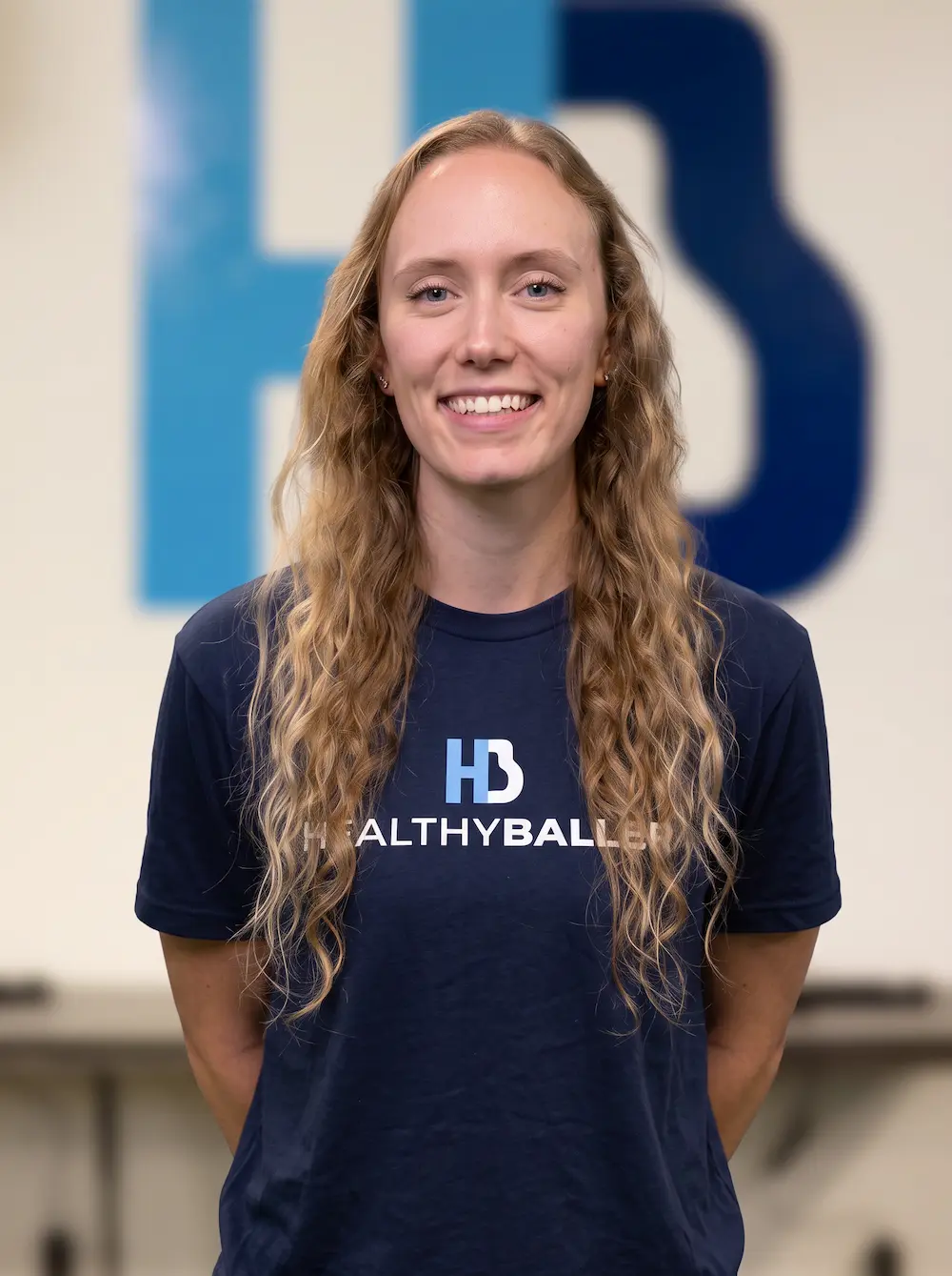 Smiling HealthyBaller staff member in branded navy shirt