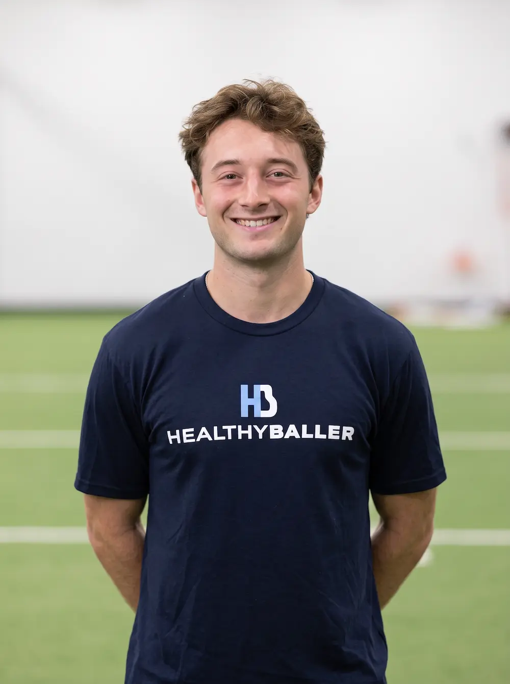 Smiling man in HealthyBaller shirt on indoor turf